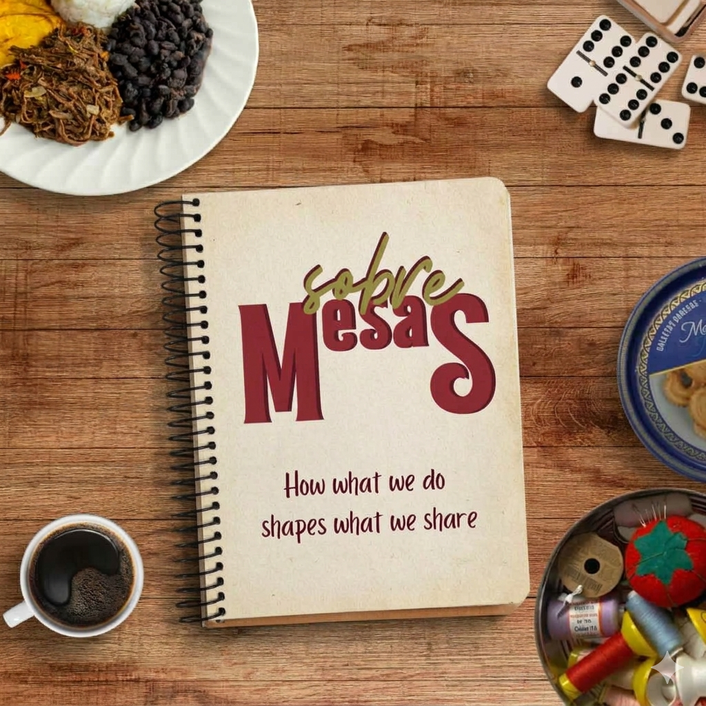 Overhead view of a wooden table with a plate of food, dominos, a cup of coffee, and a cookie tin filled with sewing supplies. All these items surround a spiral notebook that reads Sobre Mesas- How what we do shapes what we share